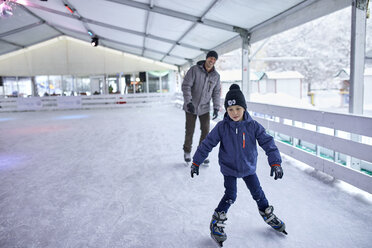 Vater und Sohn laufen gemeinsam Schlittschuh und haben Spaß auf der Eisbahn - ZEDF01871