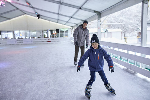 Vater und Sohn laufen gemeinsam Schlittschuh und haben Spaß auf der Eisbahn - ZEDF01871