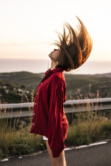 Junge Frau wirft ihr Haar auf der Landstraße bei Sonnenuntergang - ACPF00398