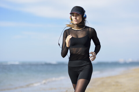 Sportliche Frau beim Laufen am Strand, lizenzfreies Stockfoto
