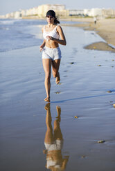 Sportliche Frau beim Laufen am Strand - JSMF00771