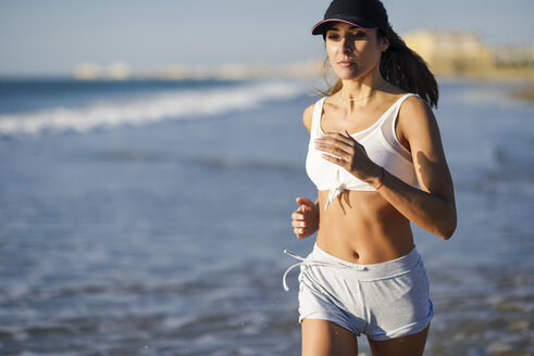 Sportliche Frau beim Laufen am Strand - JSMF00773