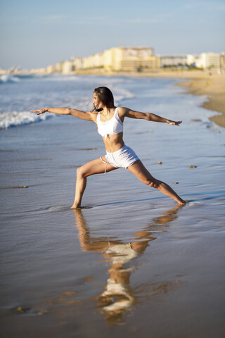 Sportliche Frau beim Yoga am Strand, lizenzfreies Stockfoto