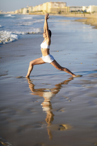 Sportliche Frau beim Yoga am Strand, lizenzfreies Stockfoto