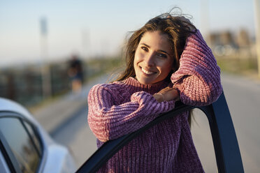 Portrait of smiling woman leaning on car door - JSMF00793