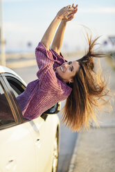 Portrait of happy woman leaning out of car window - JSMF00794