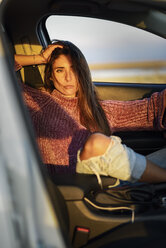 Portrait of serious woman sitting in car at sunset - JSMF00796