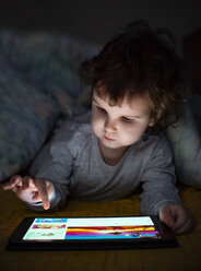 Little girl using digital tablet in bed under blanket - DEGF00963