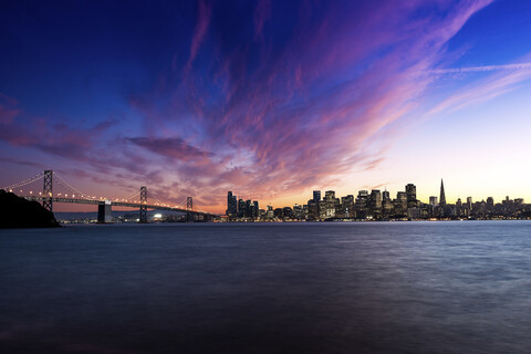 USA, Kalifornien, Skyline von San Francisco und Oakland Bay Bridge bei Sonnenuntergang, lizenzfreies Stockfoto