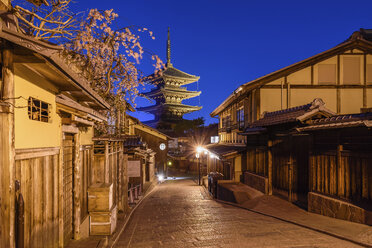 Traditional houses lining a narrow street with a pagoda in the distance, Higashiyama at night, Kyoto, Japan. - MINF10089