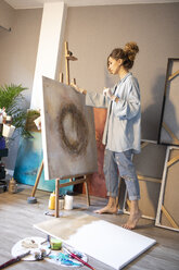 Junge Frau betrachtet das fertige Gemälde in ihrem Atelier - GRSF00071