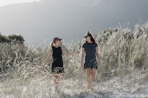 Südafrika, Westkap, Hout Bay, zwei junge Frauen gehen in den Dünen spazieren und unterhalten sich, lizenzfreies Stockfoto
