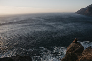 Südafrika, Westkap, Frau sitzt auf einem Felsen und betrachtet die Aussicht, gesehen vom Chapman's Peak Drive - LHPF00409