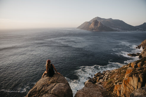 South Africa, Western Cape, woman sitting on a rock looking at view, seen from Chapman's Peak Drive - LHPF00410
