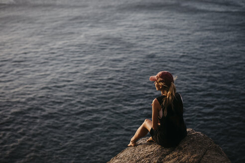 South Africa, Western Cape, woman sitting on a rock watching sunset, seen from Chapman's Peak Drive - LHPF00411
