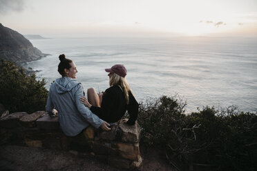 Südafrika, Westkap, zwei junge Frauen, die abends auf einer Mauer sitzen und sich unterhalten - LHPF00415