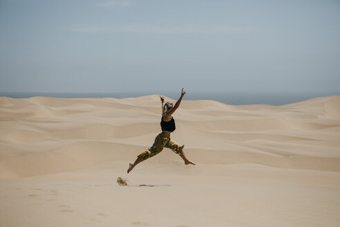 Namibia, Walvis Bay, Namib-Naukluft-Nationalpark, Sandwich Harbour, Frau springt in Dünenlandschaft - LHPF00430