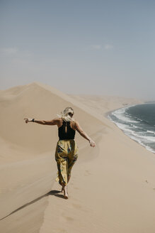 Namibia, Walvis Bay, Namib-Naukluft-Nationalpark, Sandwich Harbour, Frau spaziert in Dünenlandschaft am Meer - LHPF00438