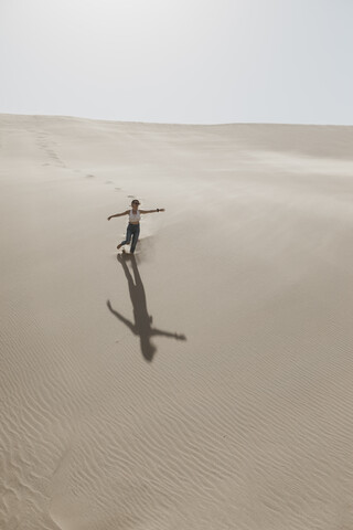 Namibia, Walvis Bay, Namib-Naukluft National Park, Sandwich Harbour, woman running in dune landscape stock photo