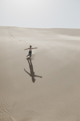 Namibia, Walvis Bay, Namib-Naukluft-Nationalpark, Sandwich Harbour, Frau läuft in Dünenlandschaft, lizenzfreies Stockfoto