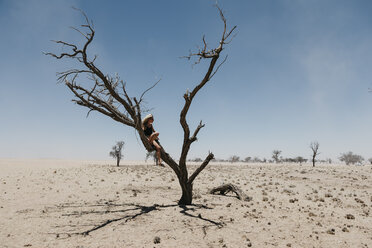 Namibia, Weg zum Sossusvlei, Frau sitzt in totem Baum in der Wüste - LHPF00446