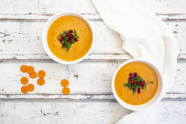 Bowl of carrot ginger coconut soup with topping of parsley and pomegranate seed - LVF07726