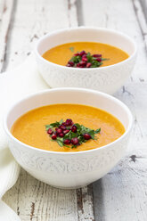 Bowls of carrot ginger coconut soup with topping of parsley and pomegranate seed - LVF07727