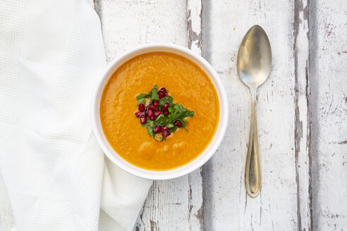 Bowl of carrot ginger coconut soup with topping of parsley and pomegranate seed - LVF07728