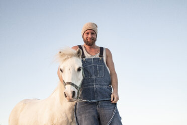 Porträt eines lächelnden Mannes mit Pony unter blauem Himmel - KBF00485