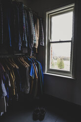 Interior view of walk-in wardrobe with sash window and clothing on clothes rails. - MINF10180