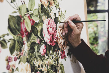 Close up of artist working on painting of pink tea roses, leaves, berries and other flowers. - MINF10263
