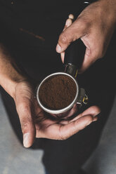 Nahaufnahme einer Person, die eine Espressomaschine mit gemahlenem Espresso in der Hand hält. - MINF10327