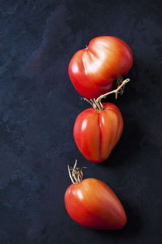 Drei Oxheart-Tomaten auf dunklem Hintergrund, lizenzfreies Stockfoto