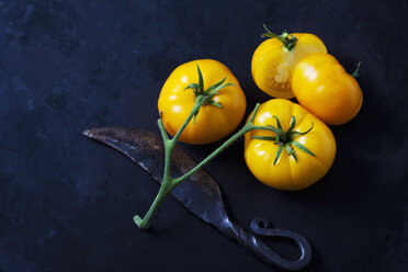 Ganze und geschnittene Azoychka-Tomaten und ein altes Messer auf dunklem Grund - CSF29281