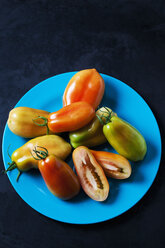 Ganze und geschnittene San Marzano-Tomaten auf hellblauem Teller - CSF29284
