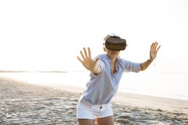 Thailand, Frau mit Virtual-Reality-Brille am Strand im Morgenlicht - HMEF00186