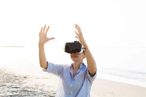 Thailand, Frau mit Virtual-Reality-Brille am Strand im Morgenlicht - HMEF00192