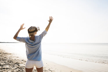 Thailand, Frau mit Virtual-Reality-Brille am Strand im Morgenlicht - HMEF00197