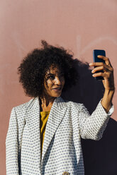 Schöne Frau steht vor einer Wand und macht Fotos mit ihrem Smartphone - BOYF01313
