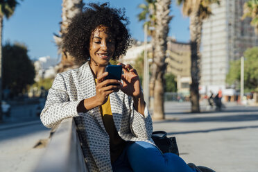 Schöne Frau sitzt auf einer Bank in der Stadt und macht Fotos mit ihrem Smartphone - BOYF01320