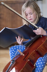 Porträt eines blonden Mädchens mit Cello und Bogen, das auf Noten blickt - HAMF00561