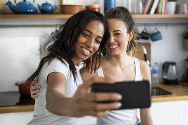 Two happy girlfriends taking a selfie at home - GIOF05649