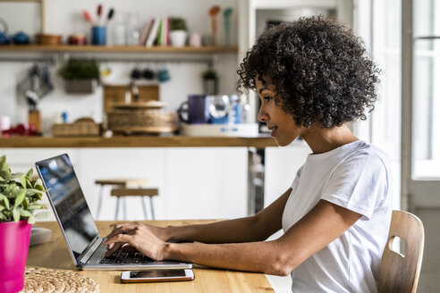 Woman using laptop at table at home - GIOF05653