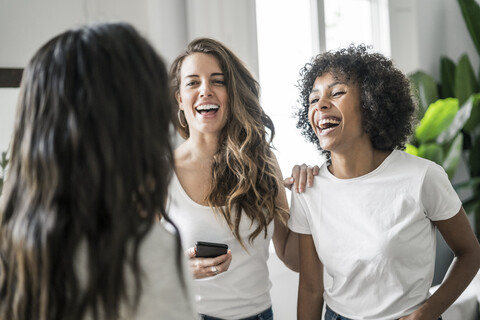 Drei glückliche Frauen beim geselligen Beisammensein zu Hause, lizenzfreies Stockfoto
