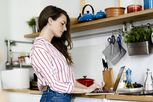Frau benutzt Laptop in der Küche zu Hause - GIOF05677