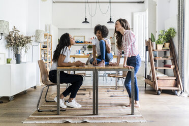 Three happy women talking at table at home - GIOF05689