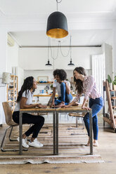Drei glückliche Frauen unterhalten sich am Tisch zu Hause - GIOF05690