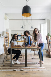 Portrait of three happy women at table at home - GIOF05691