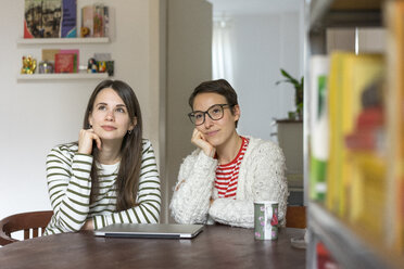 Zwei Freundinnen sitzen zu Hause am Tisch und träumen vor sich hin - MOEF01929