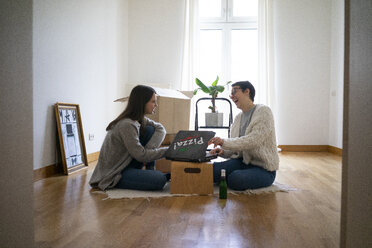 Young women sitting on floor of their new home, eating pizza - MOEF01931